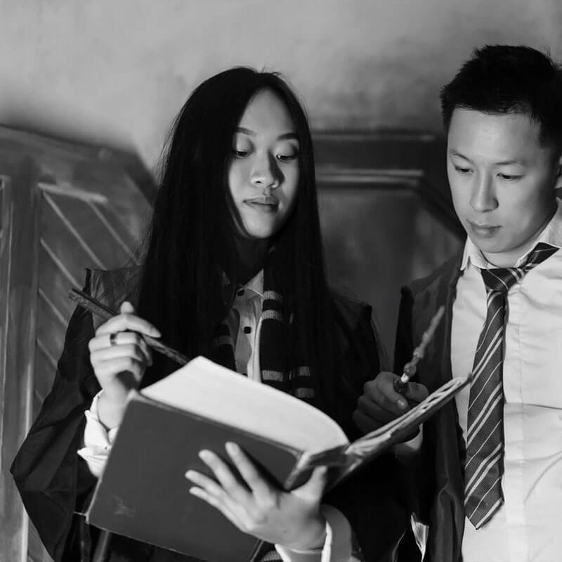 black and white photo of a girl and a boy dressed as wizards and reading a book 1