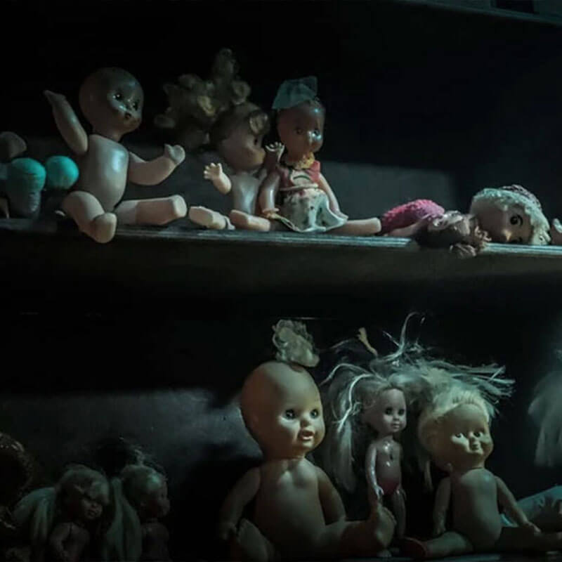 lots of creepy dolls on shelves in a dark room 1
